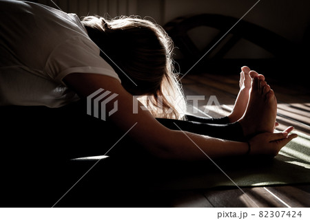 Beautiful young woman stretching in yoga pose on mat 82307424