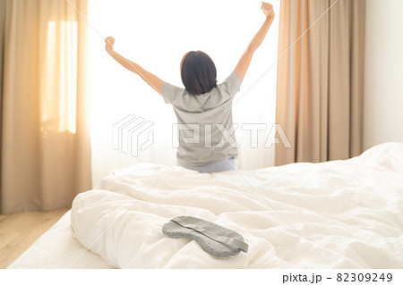 Sleeping mask on a bed with stretching woman in the background 82309249