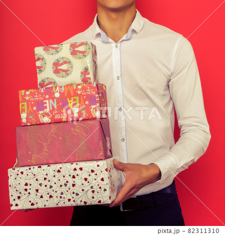 Handsome asian businessman holding gift box over red background 82311310
