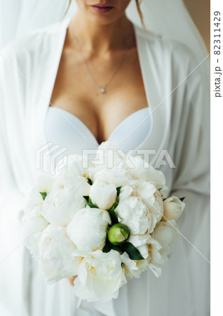 morning of the bride in the hotel room. slightly blurred image of a bouquet in the hands. 82311429