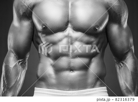 Young athletic man pumping up muscles in the gym at workout. Sport and health care concept background 82316379