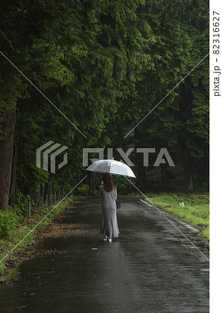 雨の日に傘をさして歩く女性の後ろ姿 82316627