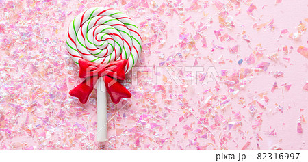 Sweet Lollipop with red bow on pink Background with shiny glitter with copy space Sweet Lollipop with red bow on pink Background with shiny glitter with copy space 82316997
