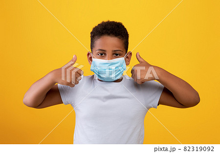 Funny black boy wearing protective face mask, showing thumb ups Funny black boy wearing protective face mask, showing thumb ups 82319092