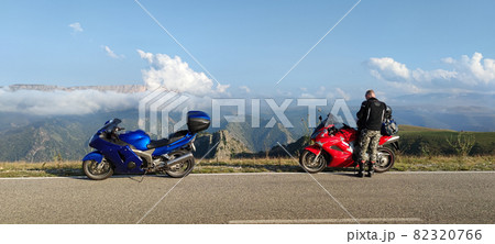 Traveller and motorcycles on road 82320766