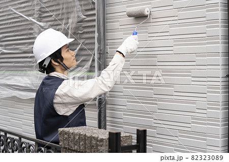 ローラーで戸建て住宅の外壁を塗る塗装職人 82323089