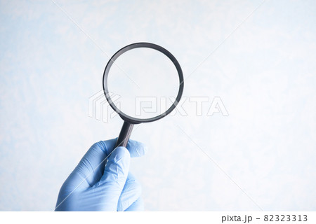 hand holding magnifying glass against white hand holding magnifying glass against white 82323313
