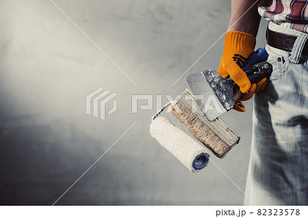 Construction worker man and concrete plaster wall. Hand and construction tools for house renovation 82323578