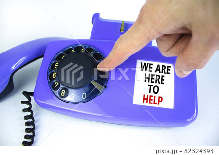 We are here to help symbol. Old blue rotary dial telephone. Words 'we are here to help'. Beautiful white background. Business, help is here and support concept, copy space. Businessman hand. We are here to help symbol. Old blue rotary dial telephone. Words 'we are here to help'. Beautiful white background. Business, help is here and support concept, copy space. Businessman hand. 82324393