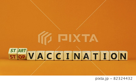 Start vaccination symbol. Turned wooden cubes and changed words 'stop vaccination' to 'start vaccination'. Beautiful orange background, copy space. Medical and covid-19 pandemic concept. 82324432