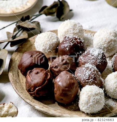 Raw vegan coconut chocolate candy balls over white with eucalyptus branches 82324663