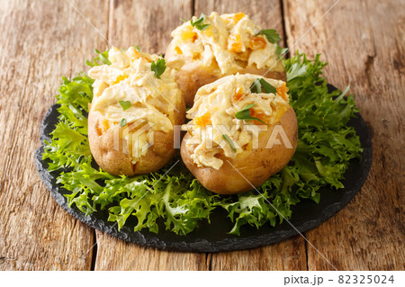 English food baked potatoes topped with coronation chicken salad with spices and dried apricots close-up on a slate board. horizontal English food baked potatoes topped with coronation chicken salad with spices and dried apricots close-up on a slate board. horizontal 82325024
