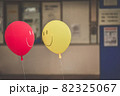 見つめ合う様に並ぶスマイル柄の赤と黄色の風船 82325067