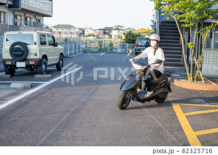 マスクをしてスクーターバイクに乗る女性 82325716