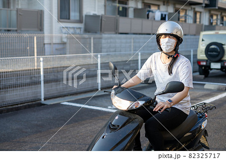 マスクをしてスクーターバイクに乗る女性 82325717