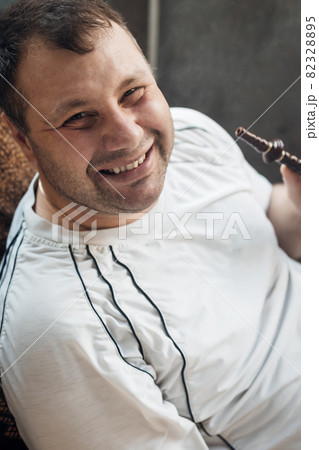 happy caucasian white young man smoking hookah and blowing smoke 82328895