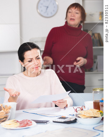 Young woman and mother with financial documents, quarrel 82330511