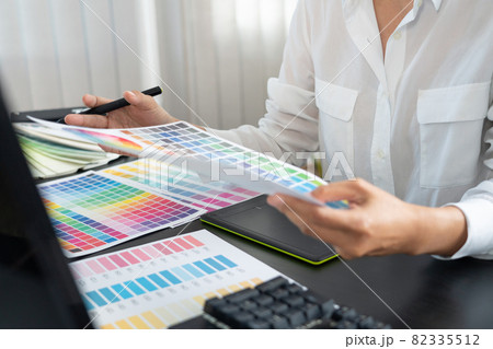 creative graphic designer choosing color scale for editing artwork while working in office. creative graphic designer choosing color scale for editing artwork while working in office. 82335512