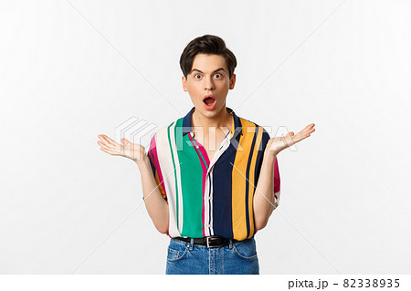 Image of surprised young male model staring at camera, spread hands sideways in complete disbelief, standing over white background Image of surprised young male model staring at camera, spread hands sideways in complete disbelief, standing over white background 82338935