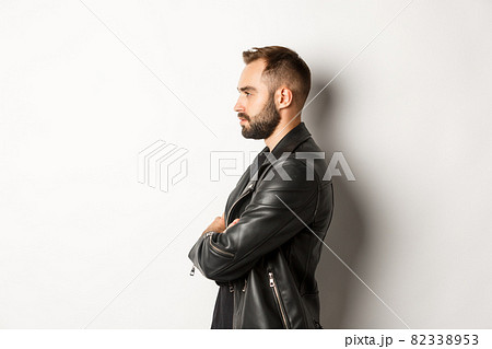 Profile of handsome serious man in leather jacket, looking left, holding hands on chest confident, white background 82338953