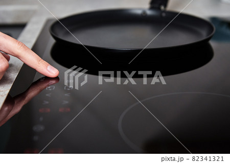 Woman hand turns on modern induction stove in the kitchen 82341321
