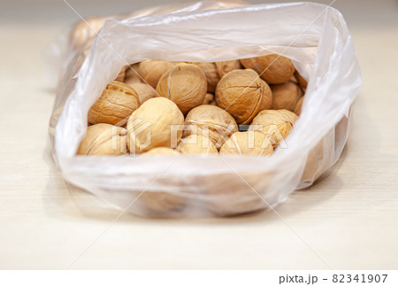A lot of whole walnuts in a bag on a white background. Healthy, organic food with a high content of protein and protein. 82341907