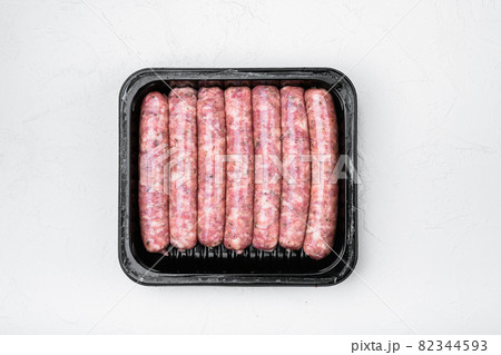 Raw meat sausages in packing box, on white stone table background, top view flat lay Raw meat sausages in packing box, on white stone table background, top view flat lay 82344593