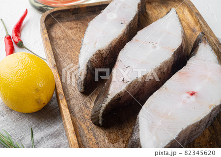 Raw fish steak, with ingredients and rosemary herbs, on white stone table background 82345620