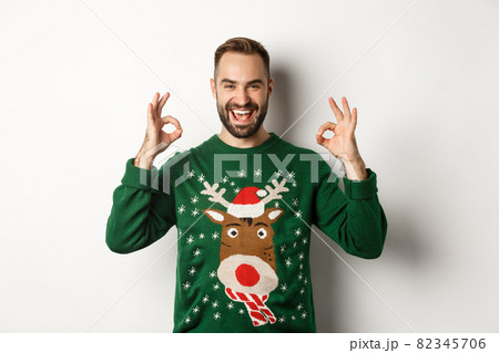 Christmas, holidays and celebration. Satisfied handsome guy in sweater, showing okay signs and smiling, praise something great, standing over white background Christmas, holidays and celebration. Satisfied handsome guy in sweater, showing okay signs and smiling, praise something great, standing over white background 82345706