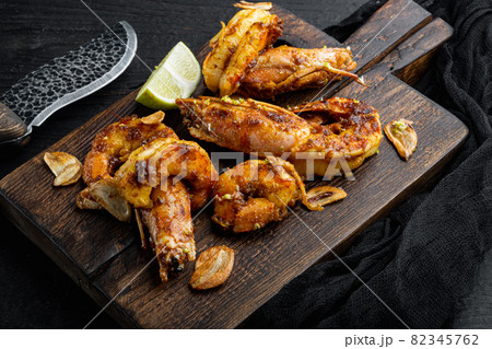 Roasted tiger prawns with Mango chutney and crispy garlic, on wooden board, on black wooden table background Roasted tiger prawns with Mango chutney and crispy garlic, on wooden board, on black wooden table background 82345762