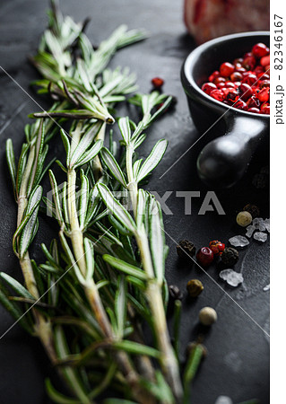 Rosemary herbs close up on black stone table with spices and raw meat near side view selective focus vertical. Rosemary herbs close up on black stone table with spices and raw meat near side view selective focus vertical. 82346167