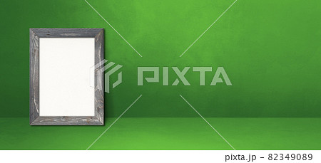 Wooden picture frame leaning on a green wall. Horizontal banner 82349089