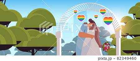 newlywed lesbian couple with flowers kissing near wedding arch transgender love LGBT community wedding celebration newlywed lesbian couple with flowers kissing near wedding arch transgender love LGBT community wedding celebration 82349460
