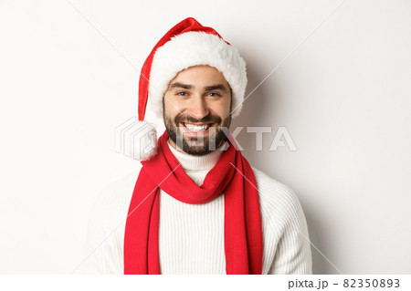 New Year party and winter holidays concept. Close-up of cheerful caucasian man celebrating Christmas in Santa hat, smiling happy, white background 82350893