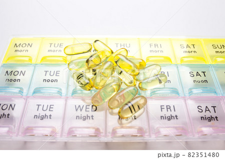 Organizer for medical pills on a white isolated background close-up. Organization of taking pills of the day. Transparent vitamins lie nearby 82351480