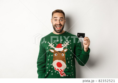 Christmas holidays and shopping concept. Cheerful man showing credit card, standing over white background 82352521