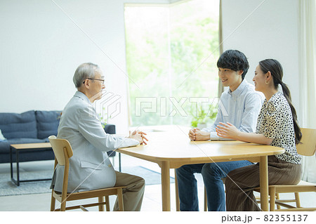 会話するシニア男性と若い夫婦 82355137