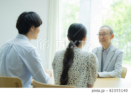 会話するシニア男性と若い夫婦 会話するシニア男性と若い夫婦 82355140
