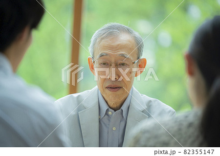 会話するシニア男性と若い夫婦 82355147