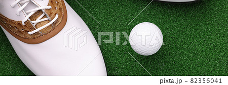 White shoes and ball lying on green golf course closeup 82356041