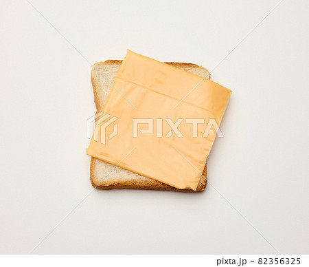 square slices of toasted bread made from white wheat flour and a slice of cheddar cheese on top. White table background square slices of toasted bread made from white wheat flour and a slice of cheddar cheese on top. White table background 82356325