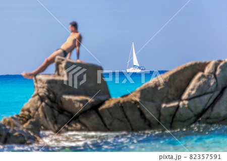 Man sunbathing on a rock against sailboats in Vibo Valentia, Calabria, Southern Italy 82357591