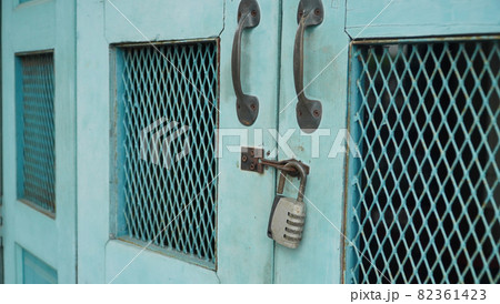Vintage wooden folding door with metal rusted latch and unlocked padlock 82361423
