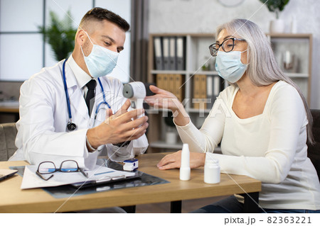 Doctor using modern thermometer for examining aged woman Doctor using modern thermometer for examining aged woman 82363221