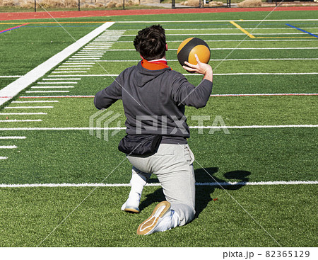 Shot put athlete on his knees trining by throwing a medicine ball Shot put athlete on his knees trining by throwing a medicine ball 82365129