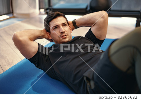 Young muscular caucasian handsome man doing abs exercises on mat Young muscular caucasian handsome man doing abs exercises on mat 82365632