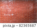Red brick wall background. Brickwork texture with scratches and cracks. Traces of white paint, cement, and concrete on wall. Photo of facade of old building. Can be used as background or wallpaper 82365687