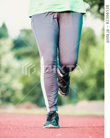 Mature woman in green singlet and gray leggings runs. Keep condition Mature woman in green singlet and gray leggings runs. Keep condition 82366536