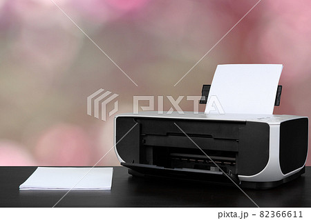 Compact laser printer on black desk against blurred background 82366611