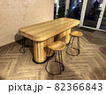 Restaurant or cafeteria in modern loft style. Large massive dinner table and chairs with steel legs are standing on old vintage floor next to decorative brick wall against reinforced plastic doors 82366843